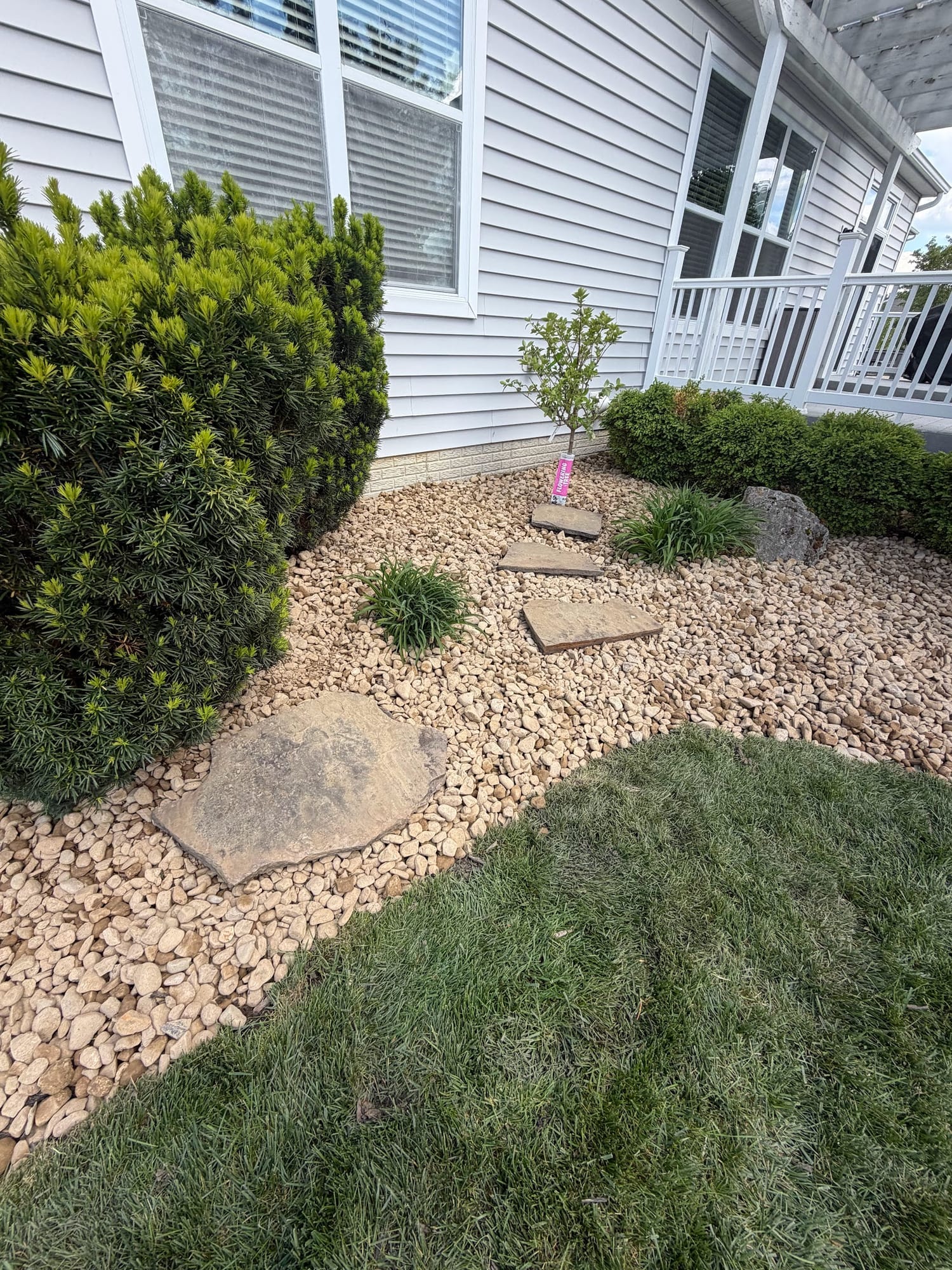 River-rock bed with trimmed shrubs at a home entrance