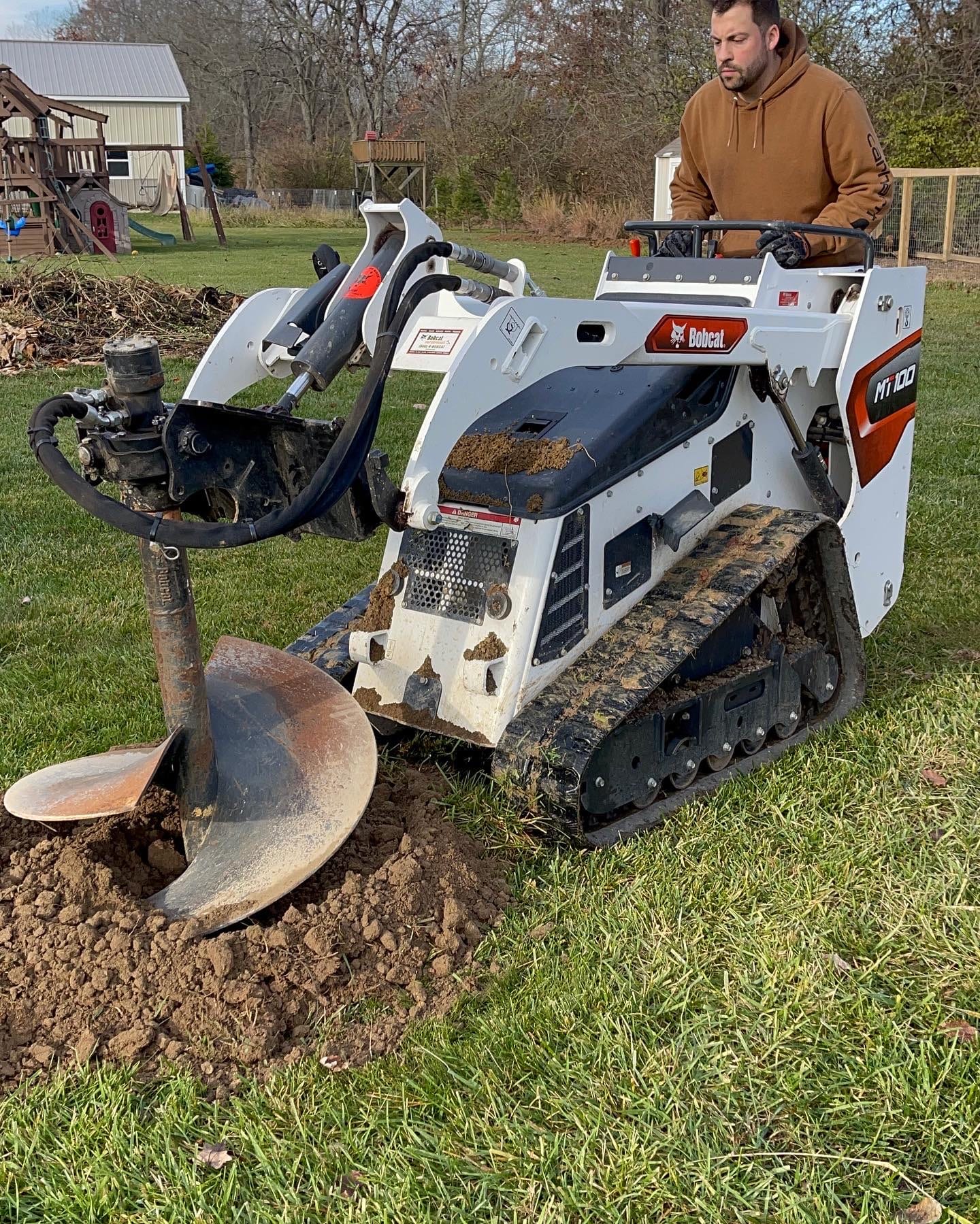 Operator grinding a stump with a tracked grinder
